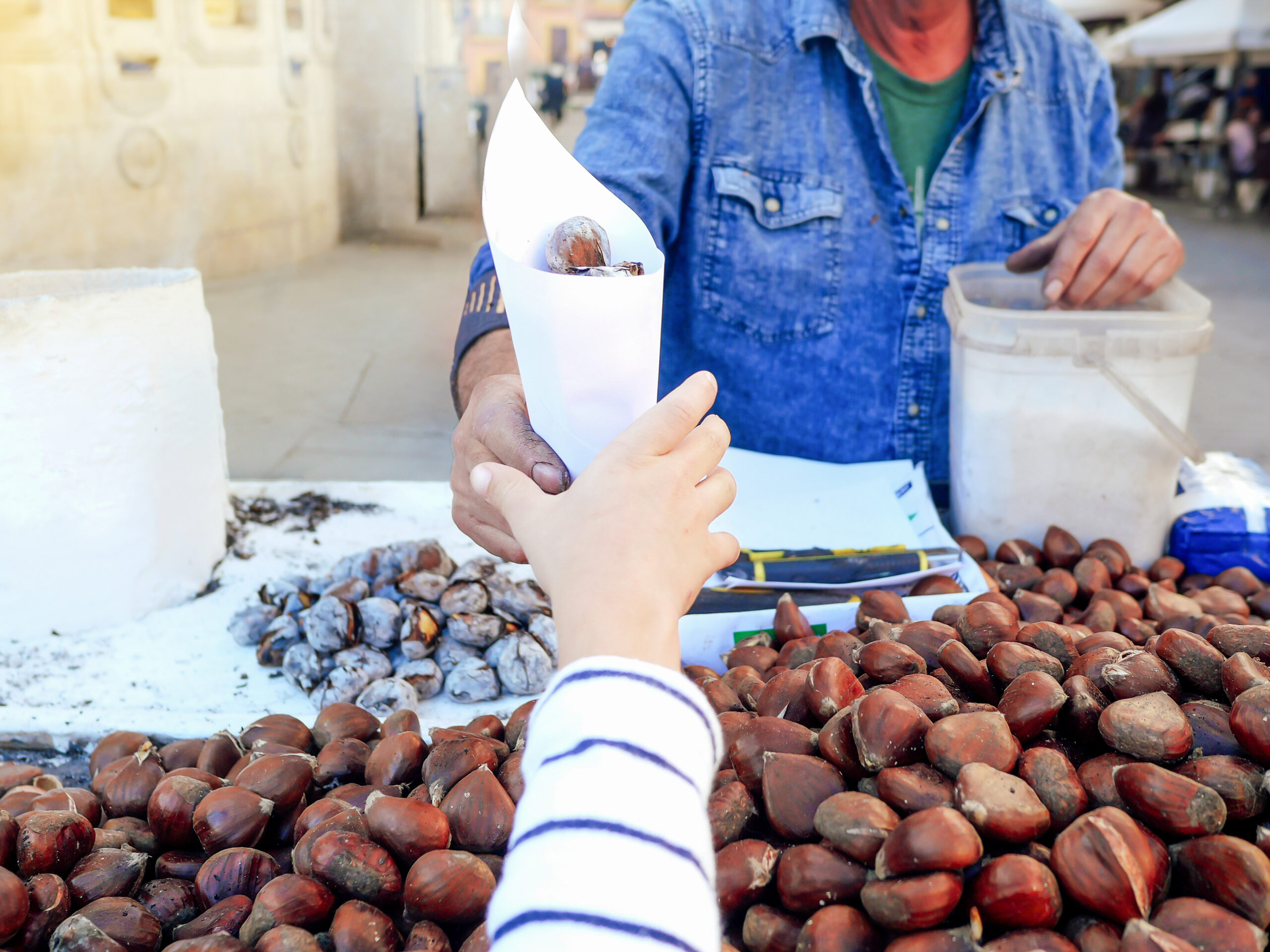 Man selling roasted chestnuts on the street to a child