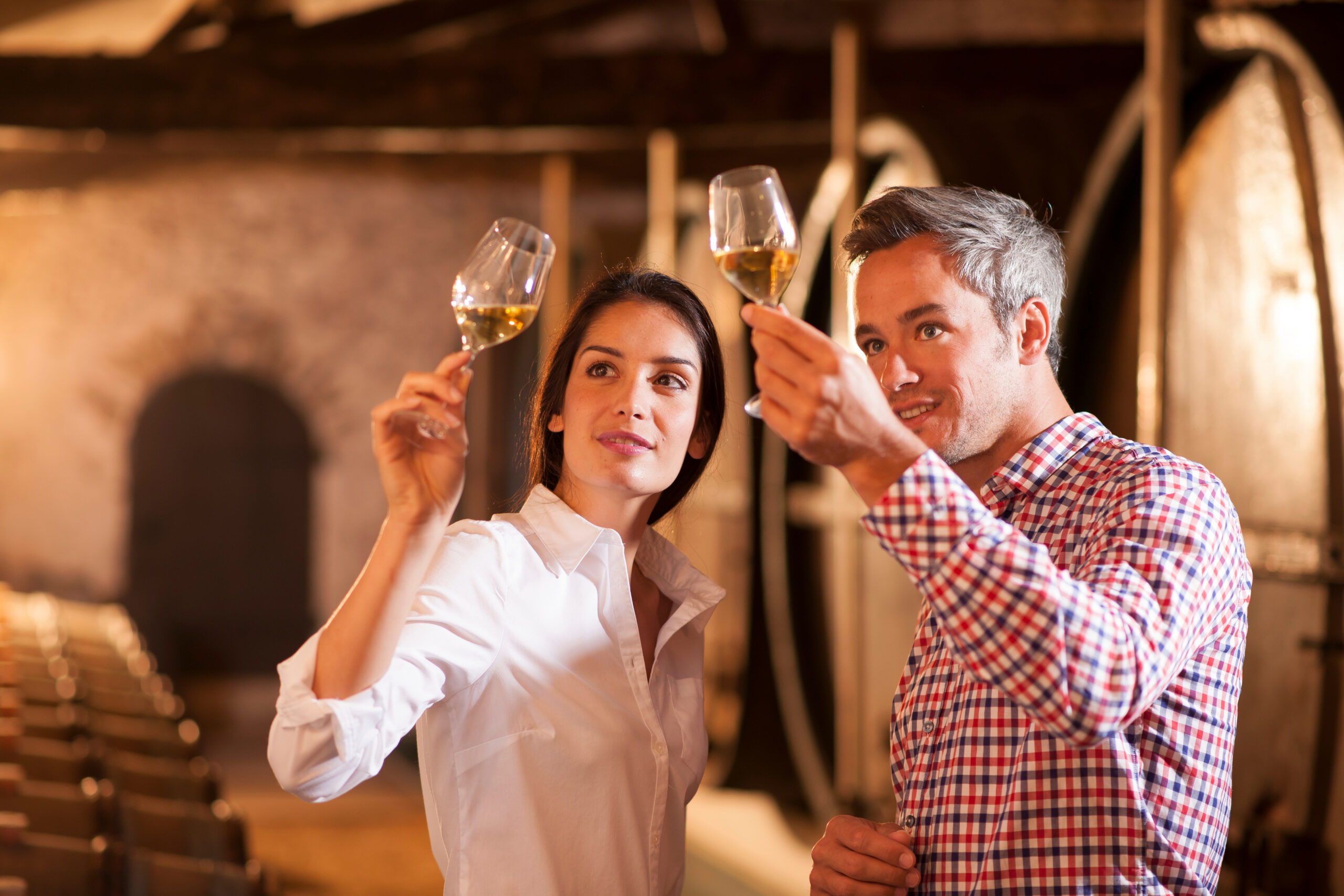 Couple tasting a glass of white wine in a traditional cellar sur